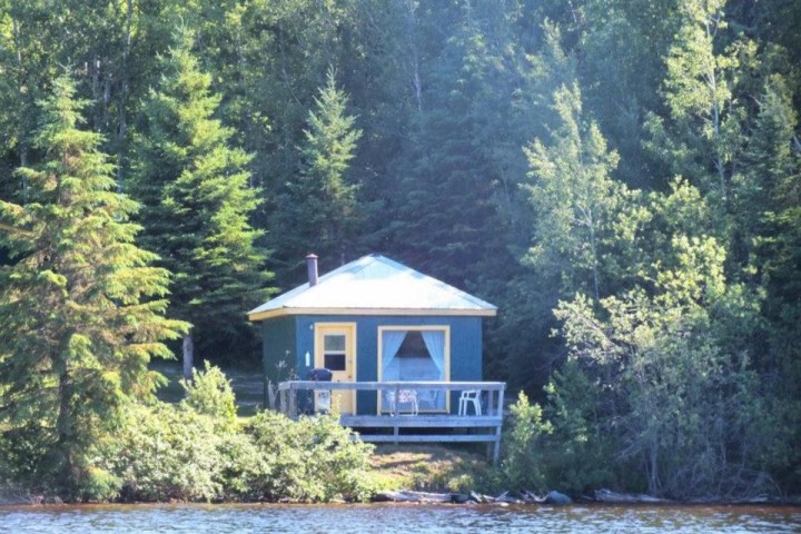 a house in the middle of a lake surrounded by forest