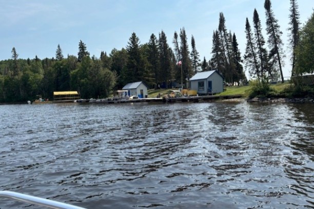 Lakeside with small cabins, dock, and trees in the background.